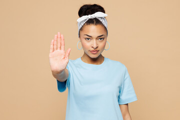 Young sad woman of African American ethnicity wear blue t-shirt headscarf casual clothes showing stop gesture with palm look camera isolated on plain pastel beige background studio. Lifestyle concept.