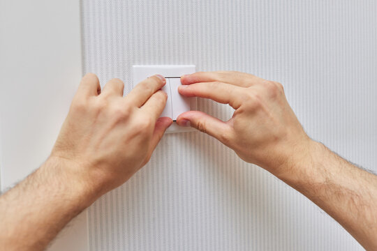 male hands of electrician installing white two-key electric light switch at home. Replacing.