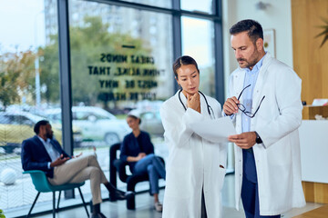Fototapeta premium Asian Woman Doctor and Asian Man Doctor Review Documents in a Modern Medical Clinic Setting