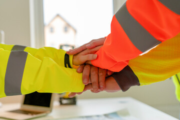 Group of construction professionals business people with hands in stack as sign of teamwork, collaboration or solidarity in workplace where everyone supporting each other