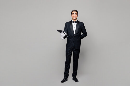 Full body young barista male waiter butler man in shirt black suit bow tie elegant uniform work at cafe hold clipboard menu taking order isolated on plain grey background Restaurant employee concept