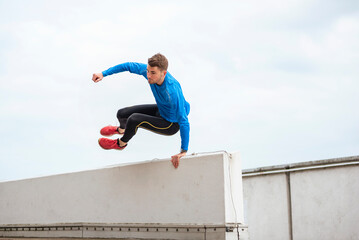 Athlete jumping over urban rooftop practicing parkour outdoors