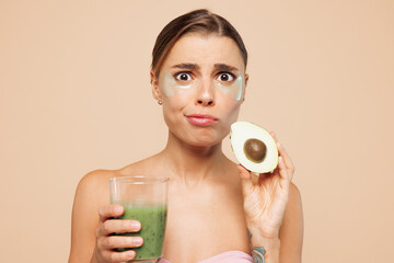 Beautiful scared sad half naked topless young woman 20s with nude make up hold avocado drink...