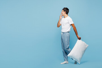 Full body side view calm young man he wearing pyjamas jam sleep eye mask rest relax at home walk go...