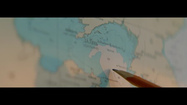 Manager plans route and marks destination on map with pencil in office. Person plots abroad delivery way to country on drawing closeup