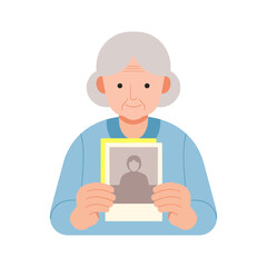 Elderly woman holding old photograph and looking thoughtfully at it  