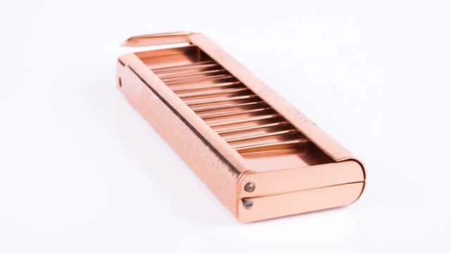 A gleaming, metallic object, detailed with floral patterns, rests on a pristine white surface