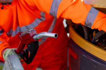 Close-up of Construction worker using fuel nozzle to refill plant and machinery with diesel fuel on building site