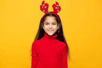 Merry smiling cheerful little girl wear red clothes fun decorative deer horns on head posing look camera isolated on plain yellow color background Happy New Year Christmas celebration holiday concept