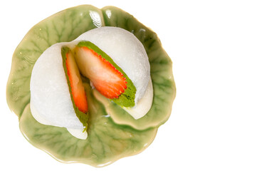Close-up of strawberry matcha daifuku on green ceramic plate, Japanese mochi dessert with red bean and matcha filling isolated on white background.