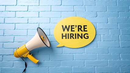 We're hiring announcement with megaphone against blue brick wall, perfect for recruitment campaigns and job opportunity promotions now