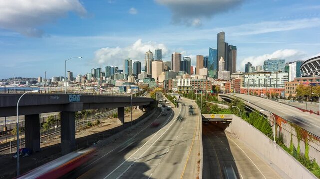 Dynamic timelapse of downtown Seattle with smooth-flowing traffic, elevated roads, and the SR 99 Tunnel entrance beneath the iconic skyline on a bright, partly cloudy day.