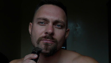 Men's face shaving. Close-up of a man's face, beard shaving, long 4K video. A man shaves his beard with a trimmer.