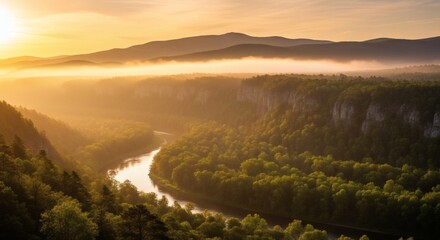 A scenic river meanders through a valley, enveloped in morning mist and bathed in warm sunlight