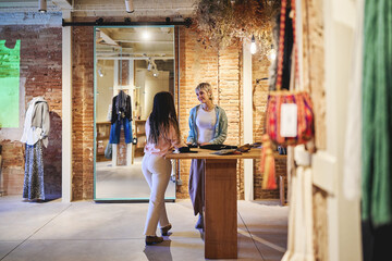 Fototapeta premium Women talking and shopping together inside stylish boutique store