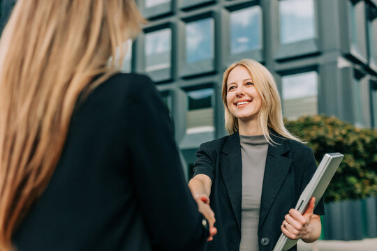 Businesswoman smiling outdoors shaking hands for successful deal