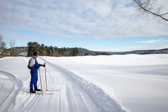 A xc skier dressed in a retro kit pauses to enjoy the snowy view