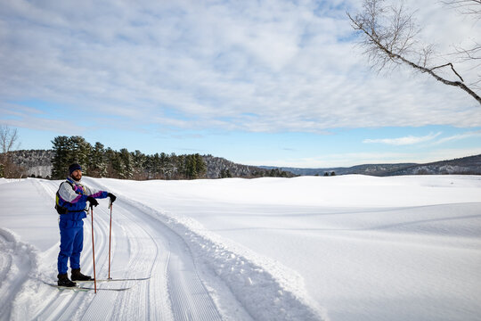 A cross country skier pauses on trail while crossing a snowy field