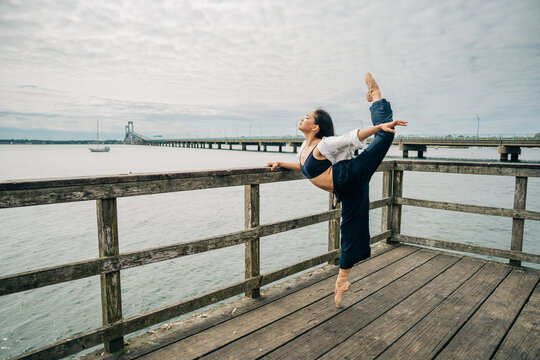 Ballerina performing dance on wooden pier by water