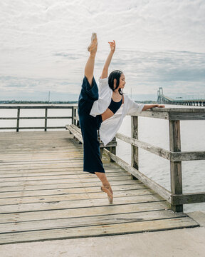 Ballerina performing flexible split on pier over water