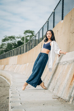 Ballerina posing in pointe shoes on urban concrete wall
