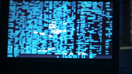 Tracking camera moving toward dark server desk, focusing on glitch code monitor and blurred racks - Powered by Adobe