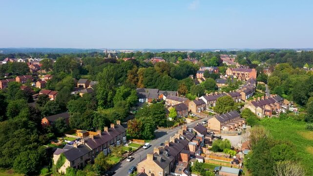 Aerial drone footage of the village of Ripon in North Yorkshire in the UK showing the historic British village and streets full of rows of terrace houses from above on a sunny day in the summer time