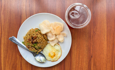 Authentic Indonesian Nasi Goreng with Fried Egg, Crackers, and Iced Tea on a Wooden Table - Southeast Asian Cuisine