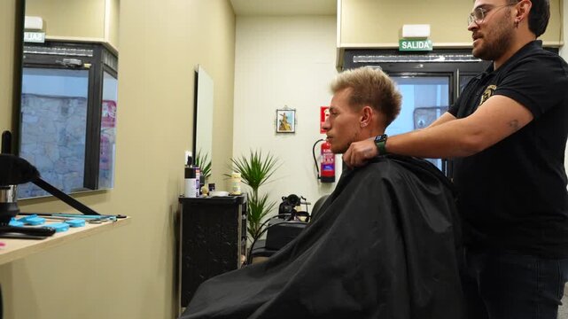 Barber places protective white band around client&rsquo;s neck before starting haircut