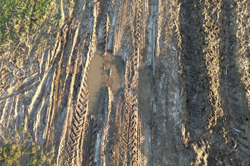 Deep tire marks in wet dirt road surface