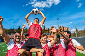 Soccer team celebrating victory with player holding ball high