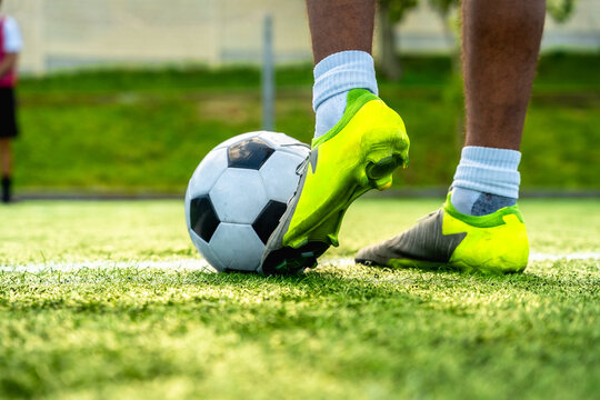 Soccer player foot controlling ball on artificial grass