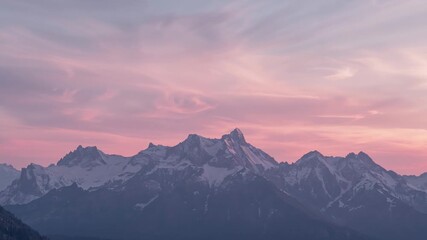 Bathing central snow-capped ridge with soft dawn light in mountain terrain, pastel clouds drifting - Powered by Adobe