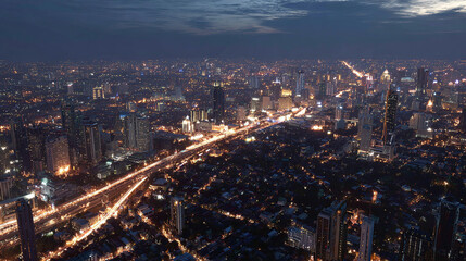 Fototapeta premium Aerial view of a cityscape at dusk, with buildings and roads illuminated by lights