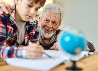 grandfather  teaching grandson and helping him with homework at home