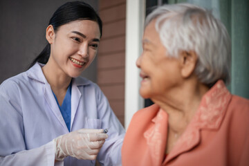 doctor holding syringe and making injection vaccine to happy senior woman