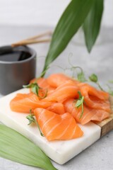 Fresh salmon sashimi with microgreens and soy sauce on grey textured table, closeup