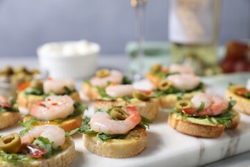 Delicious bruschettas with shrimps on light table, closeup