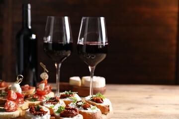 Different delicious bruschettas and red wine on wooden table
