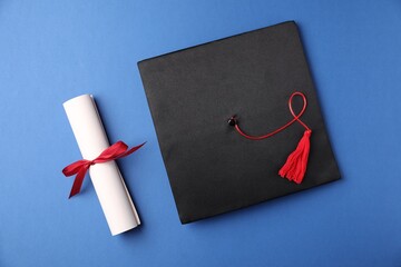 Diploma and graduation hat on blue background, flat lay