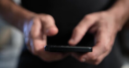Close-up of thumbs typing a message on a smartphone, zooming in and out, losing and regaining focus. Dark background for digital communication and content. - Powered by Adobe