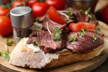 Delicious bruschettas with roast beef served on wooden table, closeup