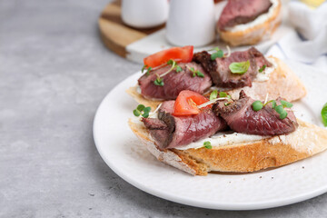 Delicious bruschettas with roast beef served on light table, closeup. Space for text