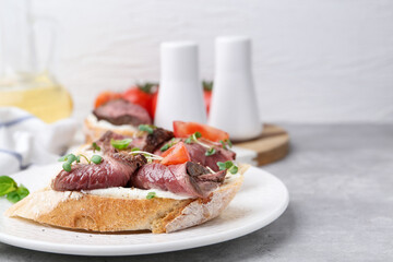 Delicious bruschettas with roast beef served on light table, closeup. Space for text