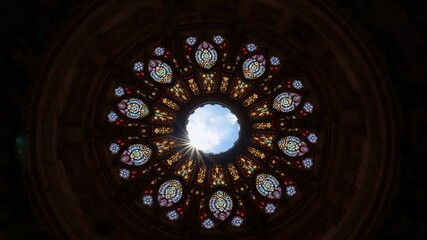Recording stained glass window glowing as sun shifting behind pane at cathedral with starburst rays - Powered by Adobe