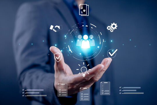 Businessman holding digital hologram of people management icons, symbolizing HR technology, recruitment, teamwork, and innovation. Perfect for concepts of human resources, business strategy.