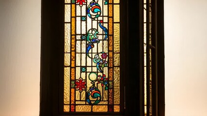 Sunlight filtering through stained-glass sending hinged panel swinging outward, revealing glazing - Powered by Adobe