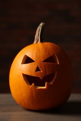 Halloween celebration. Carved pumpkin on wooden table against brick wall, closeup