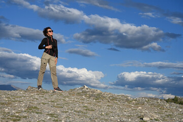 Middle-aged female tourist with a camera enjoys a mountain view
