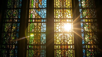 Tilting camera in church revealing three stained-glass windows, with sunlight shifting lens flares - Powered by Adobe